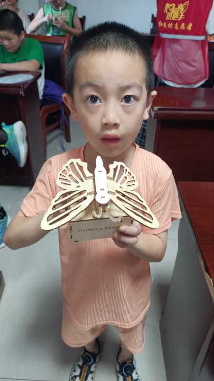图为方远航小朋友向志愿者展示他的成果